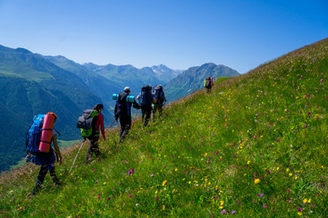Fototapeta na wymiar A group of tourists with backpacks is in the picturesque mountains.