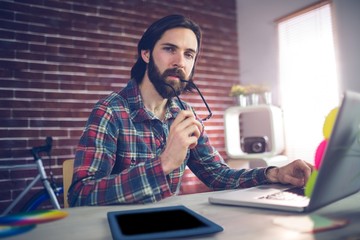 Portrait of thoughtful businessman using laptop