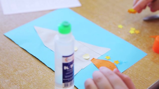 children cut out of paper and glue models of space rockets
