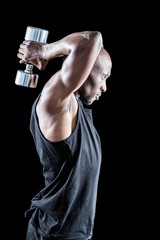Side view of muscular man exercising with dumbbell