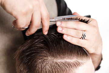 Hairdresser cuts hair of brunette satisfied client in studio