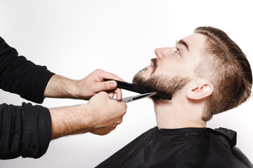 Portrait of a young man getting his beard shaved