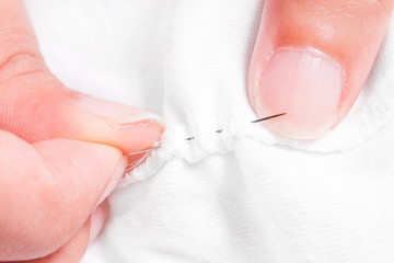 women's hands while sewing white cloth