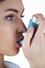 Asthmatic brunette using her inhaler 