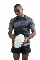 Thoughtful athlete holding rugby ball looking down