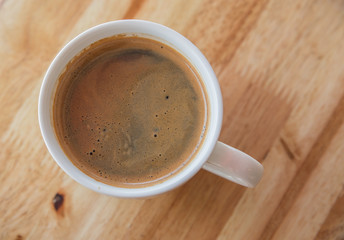 A cup of coffee with in a white cup on wooden background