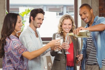 Smiling businessman pouring champagne in glass 