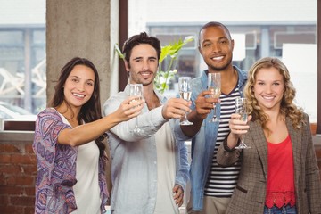 Portrait of colleagues toasting with champagne in office