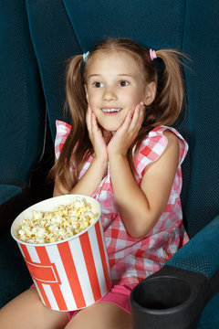 Pretty little girl watching movie at the cinema