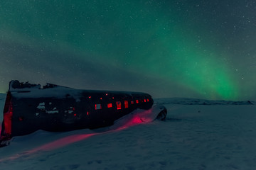 northern lights over plane wreck on the black beach in Vik, Iceland