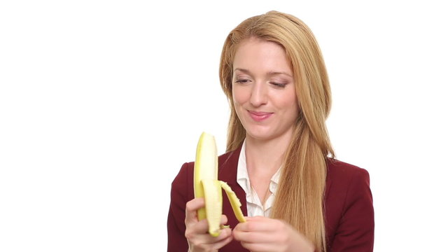 Young slim woman eats a ripe banana on a white background.