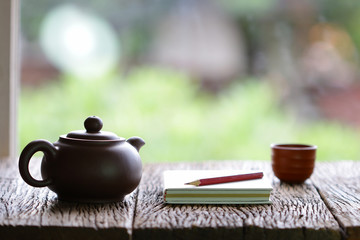 vintage old teapot clay cup and notebook  on wooden table