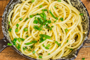 Frying pan with bucatini pasta with egg and leek