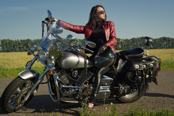 Obraz na płótnie Canvas Biker girl in a leather jacket on a motorcycle