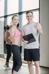 Fototapeta na wymiar smiling young woman with personal trainer in gym