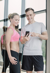 smiling young woman with personal trainer in gym