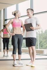 smiling man and woman with scales in gym