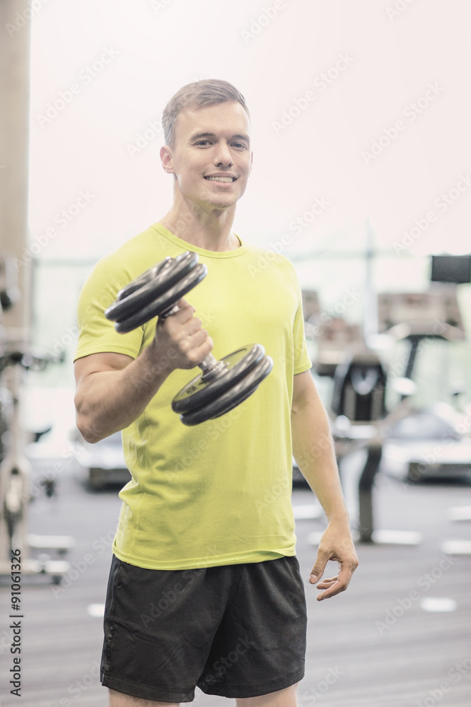 Poster smiling man with dumbbell in gym