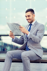 young smiling businessman newspaper outdoors