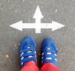Male sneakers on the asphalt road with drawn direction arrow