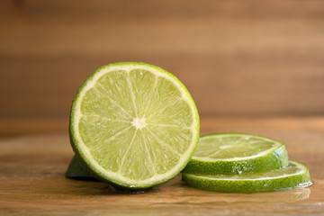 One half lime and two slices on wood background