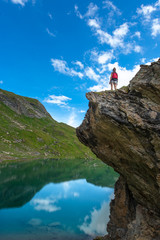 Fototapeta premium Girl on a rock above an alpine lake