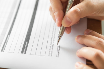 Hand with pen over application form