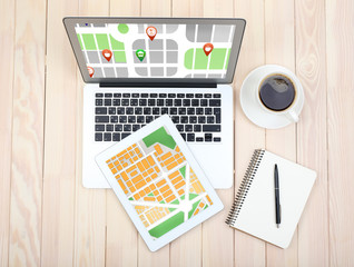 Laptop and tablet with map gps navigation application on wooden table