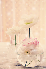 Beautiful flowers in different vases on curtains background