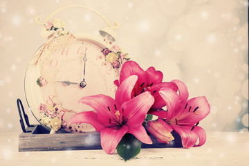 Beautiful lily and clock on wooden tray on light background