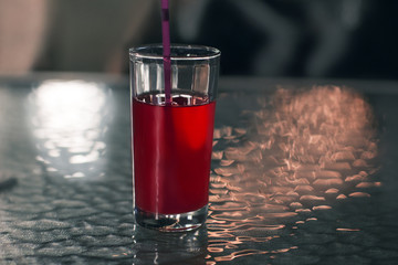 red cranberry juice with a straw on a table