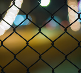 Fototapeta premium night light bokeh road behind grate on blur background