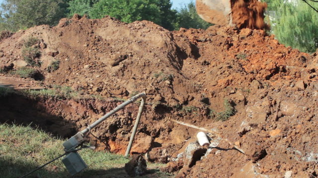 Front loader digging hole in yard.
