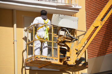 pintando una fachada sobre una grua