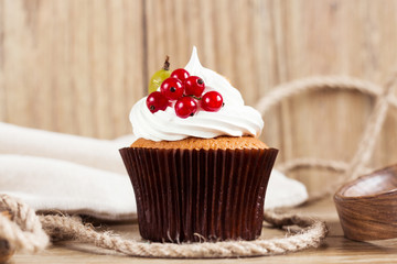 Summer cupcake with whipped cream and fruits on wooden backgroun
