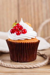 Summer cupcake with whipped cream and fruits on wooden backgroun