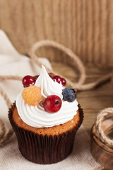 Summer cupcake with whipped cream and fruits on wooden backgroun