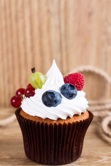 Summer cupcake decorated with cream and fresh berries