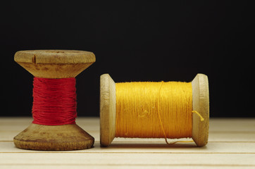 Old spool of thread with needle closeup. Tailor's work table. textile or fine cloth making.