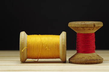 Old spool of thread with needle closeup. Tailor's work table. textile or fine cloth making.