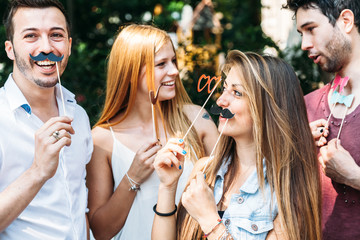 Party! A group of friends, two women and two man have fun at a party in a park with a mustache and...