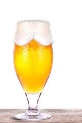 Frosty glass of light beer on a wooden table