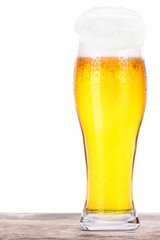 Frosty glass of light beer on a wooden table