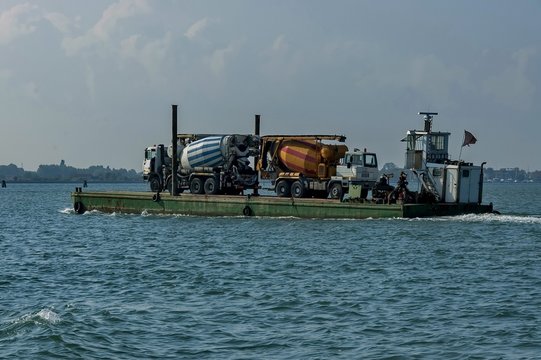 One load flat-boat ferry two concrete mixer truck via the lagoon, Italy