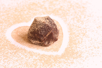 Fototapeta na wymiar isolated chocolate truffle on сocoa powder heart shape with copy space