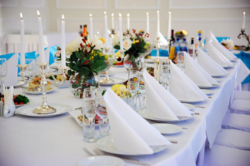 Napkins and Cutlery on white tablecloths. Candle decoration. Festive table. Serving. Wine glasses and drinks. Banquet table.