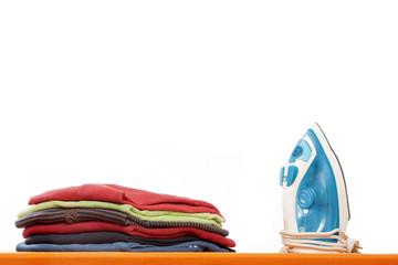 Ironing board with clothes on white background