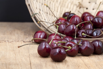Juicy ripe cherries in bamboo basket on old wooden table top.

