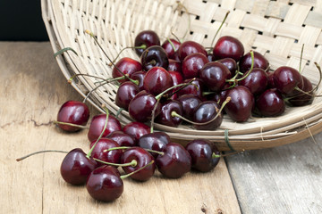 
Juicy ripe cherries in bamboo basket on old wooden table top.
