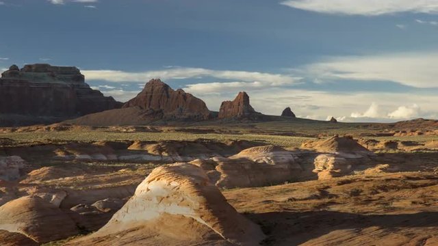 Wide time lapse shot of clouds passing over rock formations in desert landscape / Lake Powell, Utah, United States